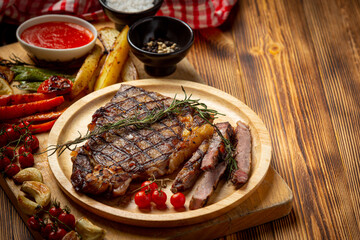 Grilled beef steak on the dark wooden background.