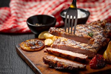 Grilled beef steak on the dark wooden background.