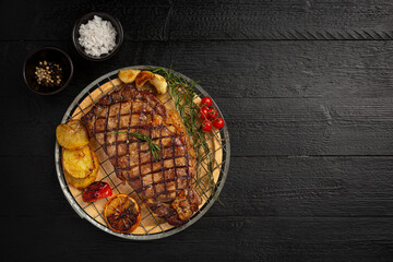 Grilled beef steak on the dark wooden background.