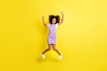 Fototapeta na wymiar Full length body size view of cheerful childish wavy-haired girl jumping fooling having fun isolated over bright yellow color background