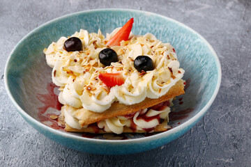 Slice cake of puff pastry with strawberry and blueberry on plate closeup