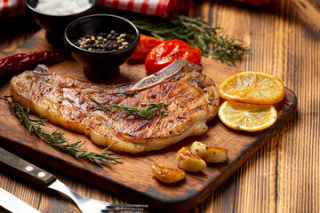 Roasted pork steak on the dark wooden background.