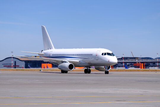 Russian Sukhoi Business Jet Airplane Taxiing on Apron of Large International Airport. Engines Running. Private Jet