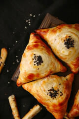 Samosa, samsa meat stuffed pies, oriental style. Uzbek national dish samosa on wood and black background top view