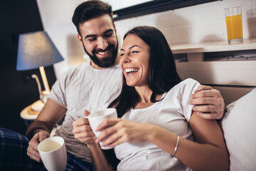 Cute couple having breakfast and drink coffee in the bedroom.