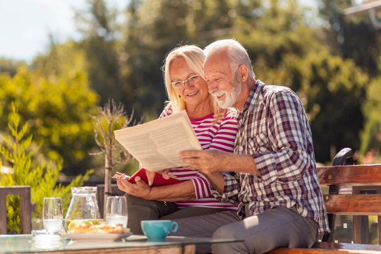 Senior couple reading newspaper in the backyard