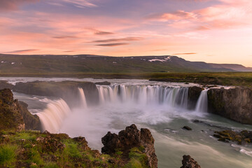 Majestic waterfall under a dramatic sky lit by midnight sun in summer. Godafoss waterfall, Iceland.