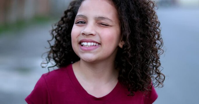 Hispanic little girl winking to camera in approval