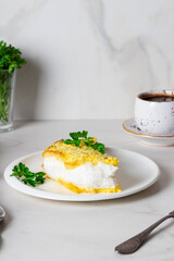 Omelette pular with parsley on the light white plate. Poulard Omelette. Mother Poulard's Omelette.