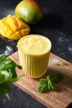 Indian mango lassie or lassi on black background. Cold ayurvedic beverage with mango. Freshness lassi made of yogurt, water, spices, fruits and ice.