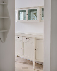 Classic wooden buffet cabinet for kitchenware in bright home interior. Storage furniture. View from hallway