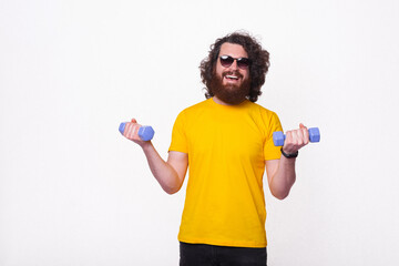 Fototapeta na wymiar Charming young bearded hipster man in yellow t-shirt working with small dumbbells
