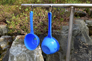 Blue plastic ladle in the mineral water reservoir - obrazy, fototapety, plakaty