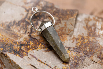 Silver metal mineral stone pendant on rocky background
