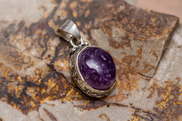 Silver metal mineral stone pendant on rocky background