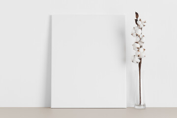 White canvas mockup with a cotton branch on the beige table.