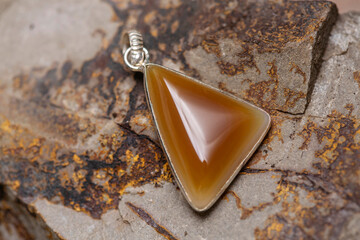 Silver metal mineral stone pendant on rocky background