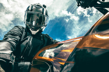 Biker in a helmet sits on a motorcycle against the background of the sky makes a selfie