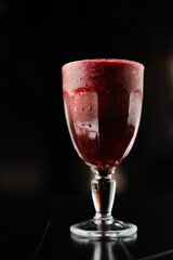 Cold red smoothie in a glass with a stem