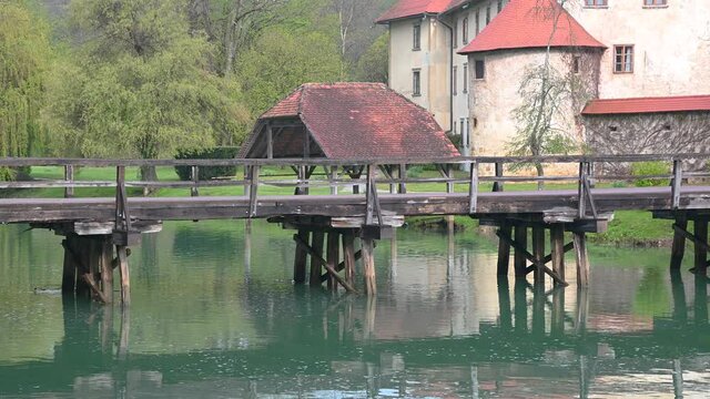 Otocec castle, the only water castle in Slovenia, located on an island in the middle of the Krka River. Famous wooden bridge over green water. Wide angle, static shot, real time