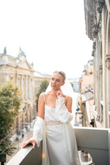 Young bride in elegant lingerie standing on balcony