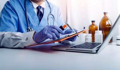 Male doctor sitting at table and writing on a document report in hospital office. Medical healthcare staff and doctor service.