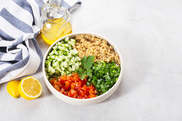 tabouleh salad  with quinoa a plate with  lemon and oil on a light grey background