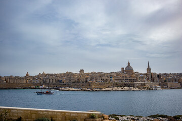 Fototapeta na wymiar Elevated view of the amazing old city of Valletta, capital of Malta and the bay with boats, scenery cloudy sky in a sunny spring day