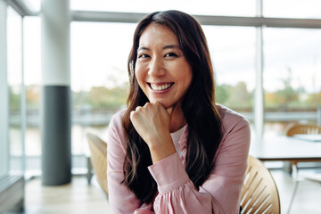 Smiling woman in office with hand on chin