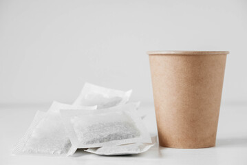 Paper cup and bags with tea on a white background. Copy, empty space for text