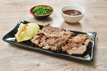 Korean fried slice pork with cabbage on plate dipping sauce and seaweed in sesame oil salad