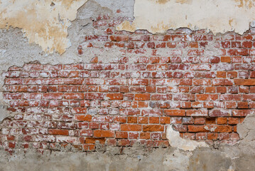 Old red brick wall background with peeling plaster. Grunge brickwall texture with stucco. Empty abstract stonewall backdrop with paint and plasterwork. Aged orange masonry with copy space