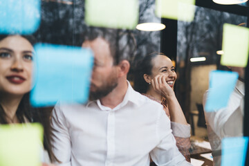 Cheerful colleagues placing stickers on glass