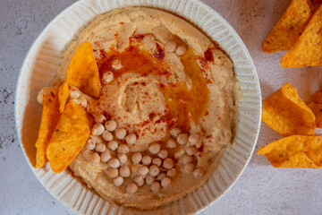 Chickpea hummus flavored with olive oil and sweet paprika and corn nachos.