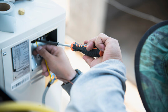 Man is installing wall compressor of air conditioner during hot season