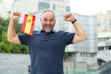 Cheerful middle aged man in the flag of Spain. Football fan.