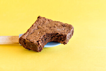Homemade chocolate brownie on yellow background.