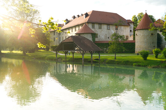 Castle Otočec on the river Krka in southern Slovenia, evening sunset scene with reflection of castle on the water