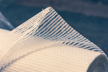 A slightly unfolded roll of fiberglass wallpaper  with the fibers ruffled at the edge. Narrow...