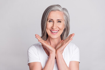Photo of cheerful aged woman happy positive toothy smile wear t-shirt isolated over grey color...