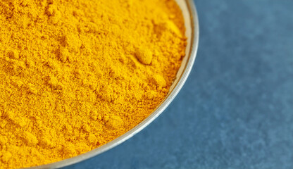 Close up picture of turmeric powder in a bowl, shallow depth of field, space for text.