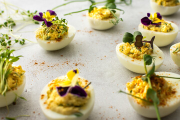 Eggs stuffed with sauce and fried onions with various microgreens, top view, delicious healthy protein snack