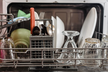 Open modern dishwasher with clean dishes after washing
