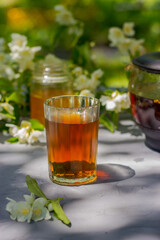 summer tea with jasmine in a glass on a wooden table in nature