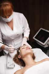 Obraz na płótnie Canvas Skincare and beauty salon cosmetology concept. Therapist in spa clinic prepare woman face for SMAS non-surgical ultrasound therapy for face lifting and skin rejuvenation