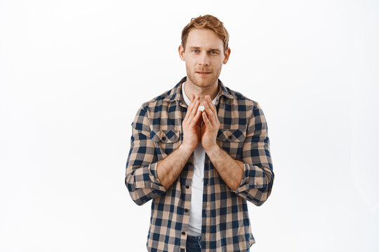 Image of thoughtful redhead man steeple fingers and looking at camera pensive, thinking about something, have a plan, standing against white background