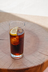 Refreshing cocktail or espresso tonic drink on small wooden table