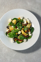 Summer salad of spinach leaves, olives, feta cheese and soy asparagus on a white plate and light background. Summer menu concept.