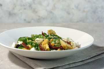 Summer salad of spinach leaves, olives,sun-dried tomato,  feta cheese and soy asparagus on a white plate and light background. Summer menu concept. horizontal arrangement.