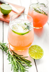 sliced lime, rosemary and natural juice in glass on white table background